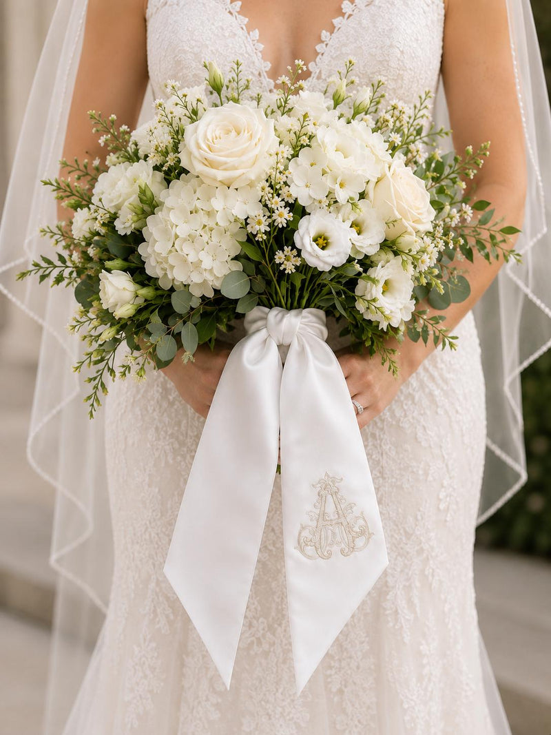 Bride holding a bouquet with a monogrammed satin bouquet sash